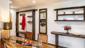A dining area with a wooden table, chairs, a lamp, and a mirror.