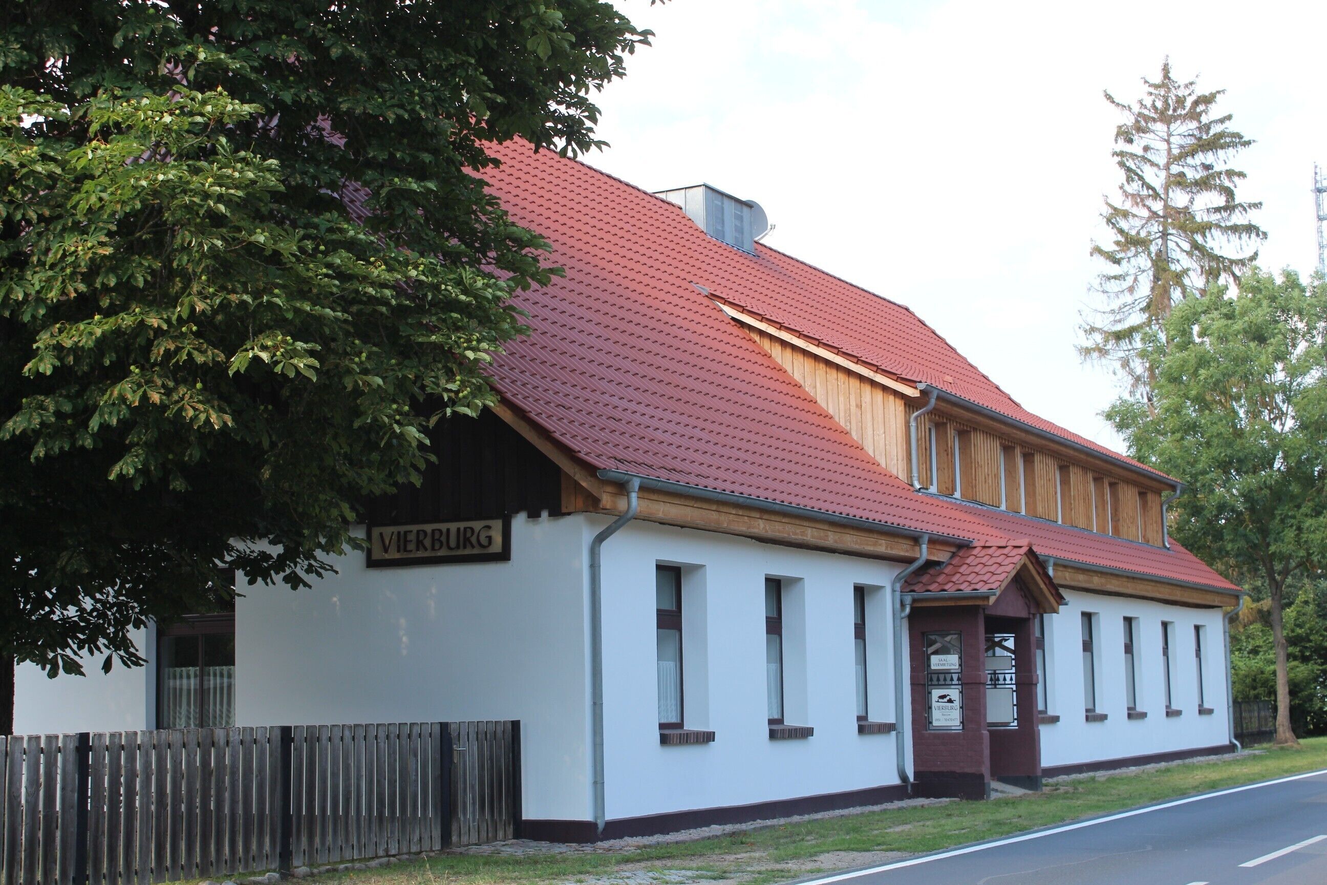 A building with a red roof, a sign reading 'VIERBURG,' and a wooden fence in front.