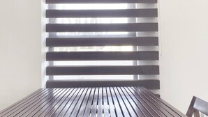 A room with a wooden table and a window with horizontal blinds. - Roma Suite A Malecon of Mazatlan (Mazatlan)