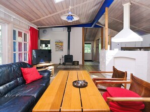 A cozy living room with a black leather sofa, a wooden coffee table, and a television. - 4 Star Holiday Home in Vig (Vig)