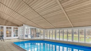 Ein Hallenbad mit Holzbalkendecke und großen Fenstern.