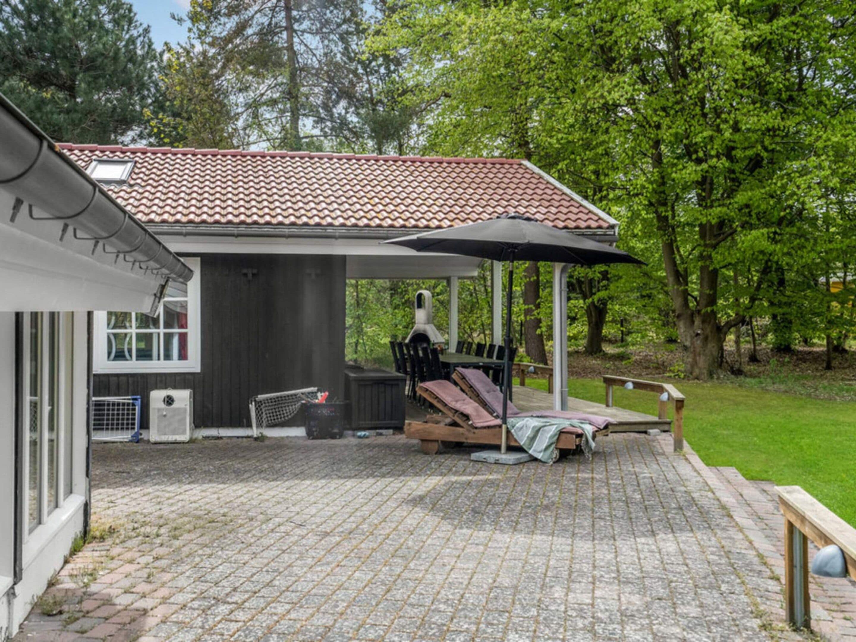 A patio with a covered seating area, a grill, and a water feature.