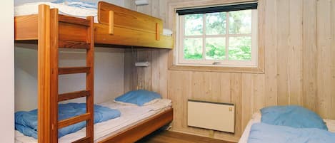 A bunk bed room with a window, wooden walls, and a radiator.