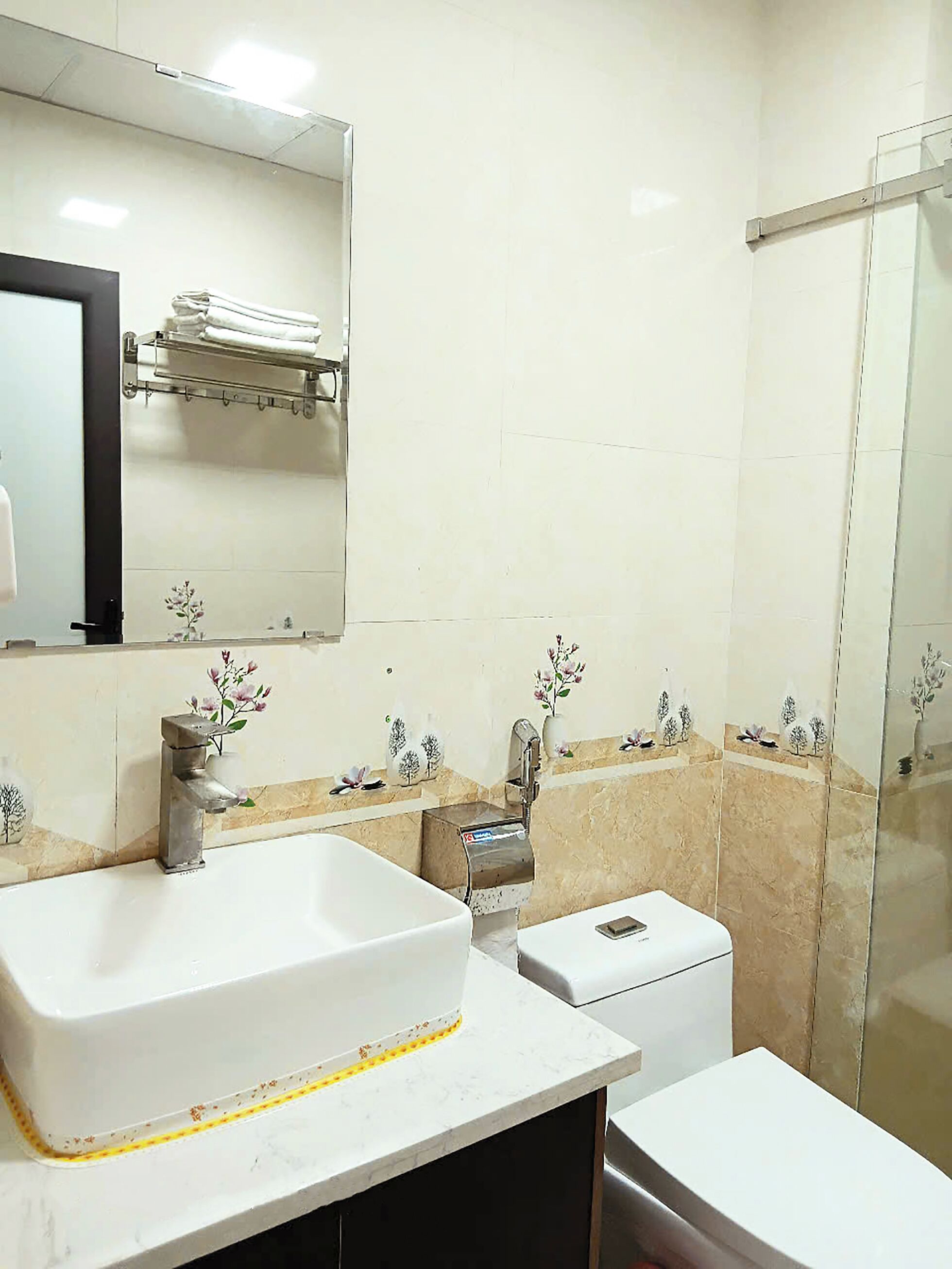 A bathroom with a large white sink, a mirror, a towel rack, a toilet, and a glass shower enclosure.