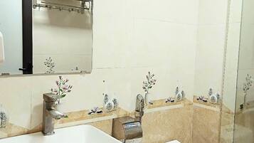 A bathroom with a large white sink, a mirror, a towel rack, a toilet, and a glass shower enclosure.