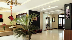 Un hall espacioso con una planta en maceta grande, un candelabro y un mostrador de recepción.