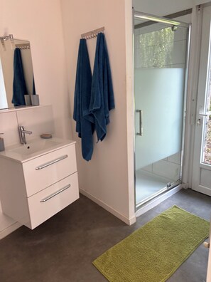 Een douche, handdoeken, zeep, toiletpapier