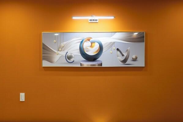 A modern art piece with abstract shapes and forms, mounted on a wall with a warm-toned background.