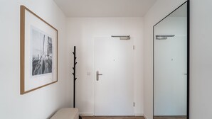 En hall med en bänk, en klädhängare, en inramad tavla och en stor spegel.
