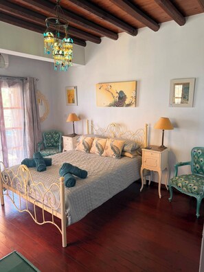 A bedroom with a bed, two nightstands, a mirror, a chair, and a chandelier.