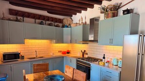 Una cocina con armarios azul claro, una mesa de comedor de madera y una estufa moderna.