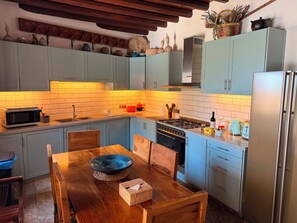 Una cocina con armarios azul claro, una mesa de comedor de madera y una estufa moderna.