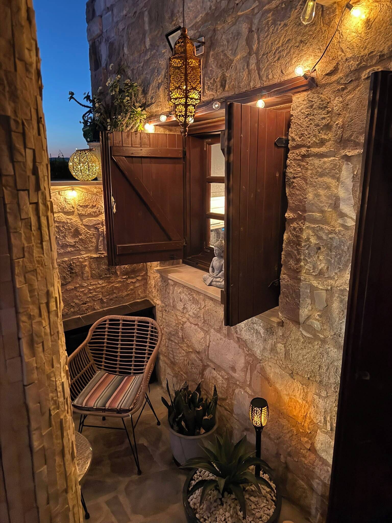 Un mur de pierre avec une porte en bois, une chaise en osier et une plante en pot.