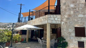 Un edificio de piedra con balcón, zona de estar al aire libre y vistas del paisaje circundante.