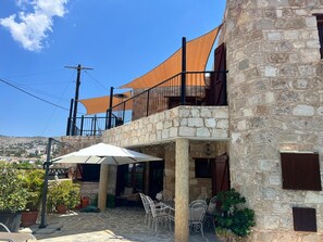A stone building with a balcony, outdoor seating area, and a view of the surrounding landscape.
