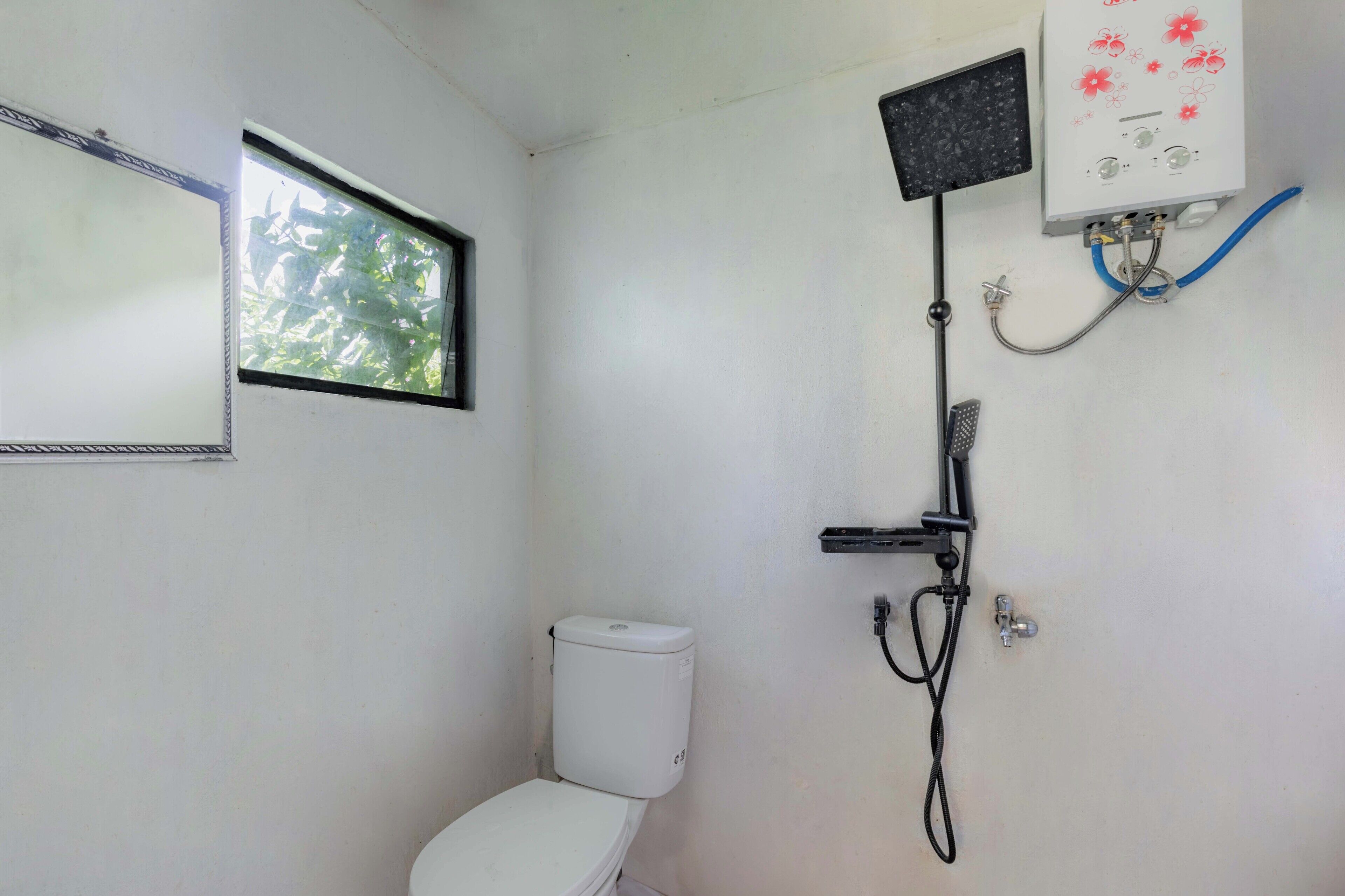 Ein kleines, schlichtes Badezimmer mit Toilette, Fenster und Duschkabine.