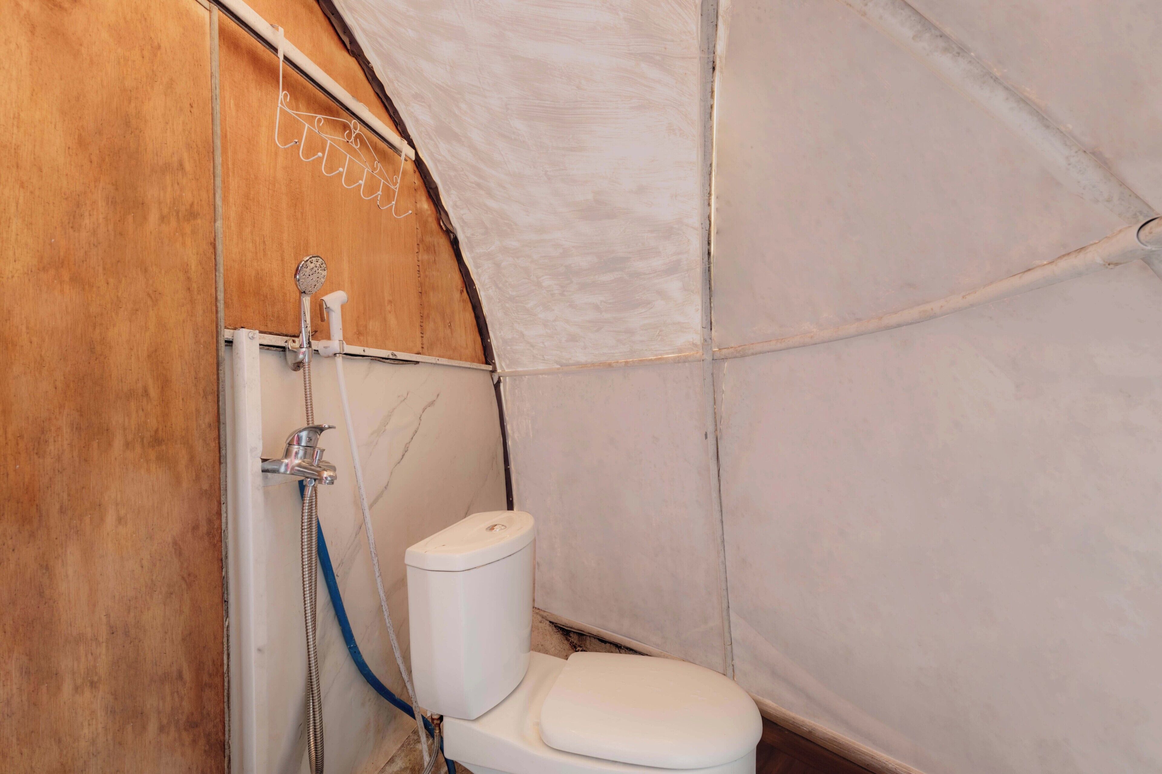 Ein kleines Badezimmer mit einer Holzwand, einer weißen Toilette und einer Duschkabine.