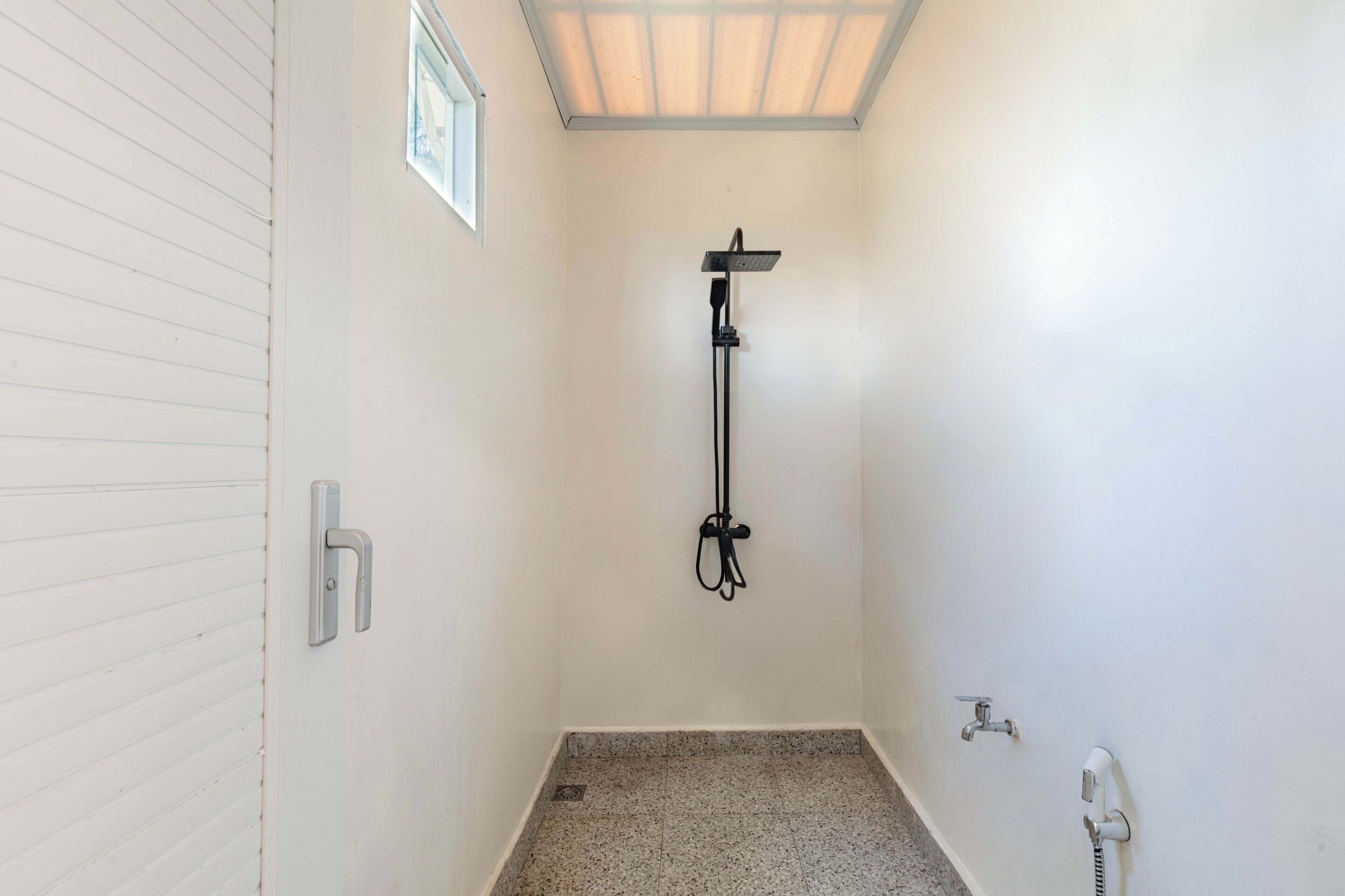 A small, white-walled bathroom with a shower, a toilet, and a sink.