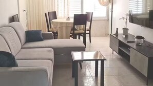 Una sala de estar moderna con un sofá, una mesa de centro y un televisor sobre un mueble.