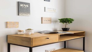 A wooden desk with a drawer, a potted plant, and several motivational wall art pieces.