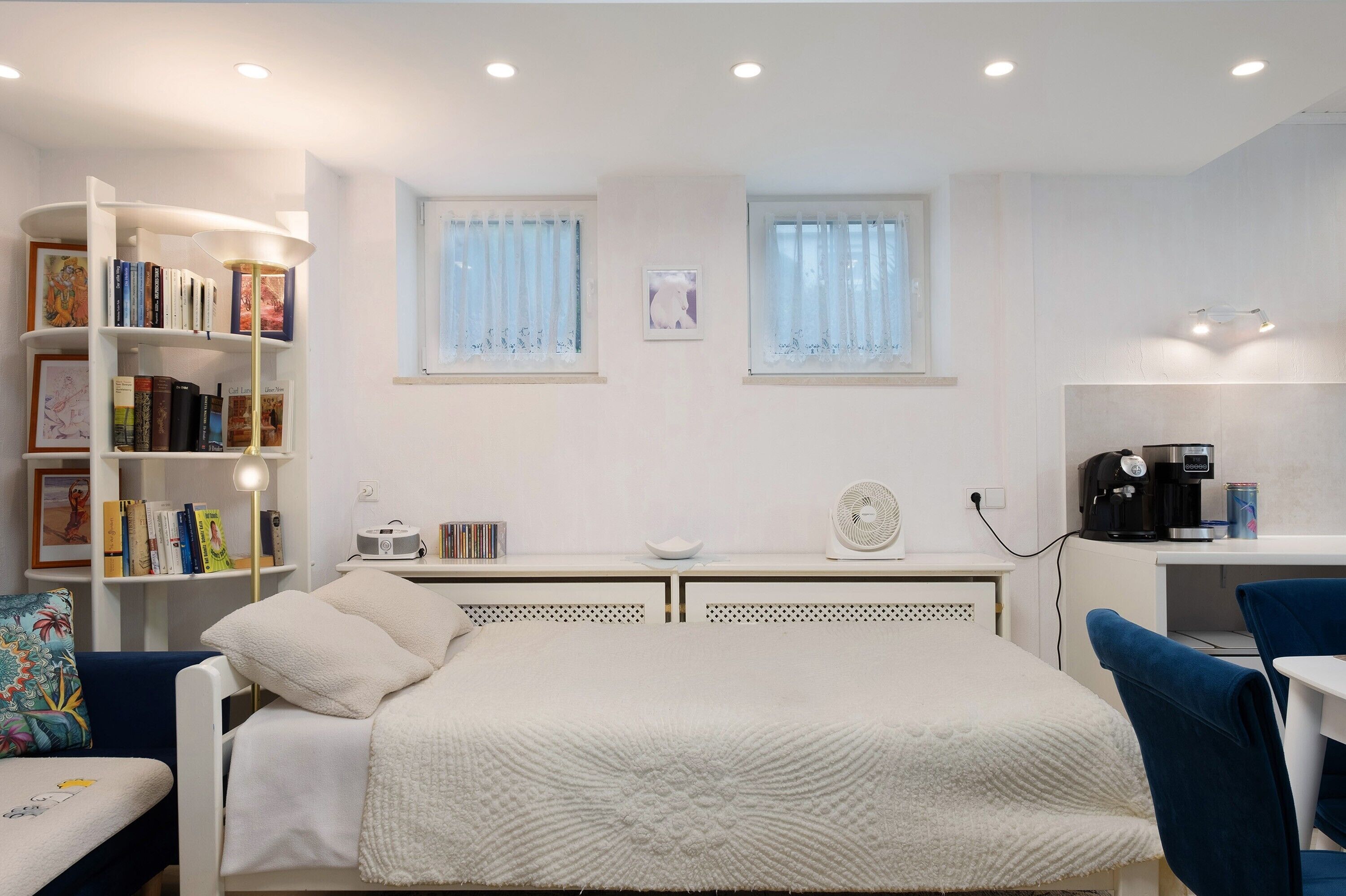 Un dormitorio con cama, estantería, escritorio y ventana.