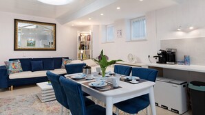 Een moderne woonkamer met een bank, eettafel en koffieapparaat.