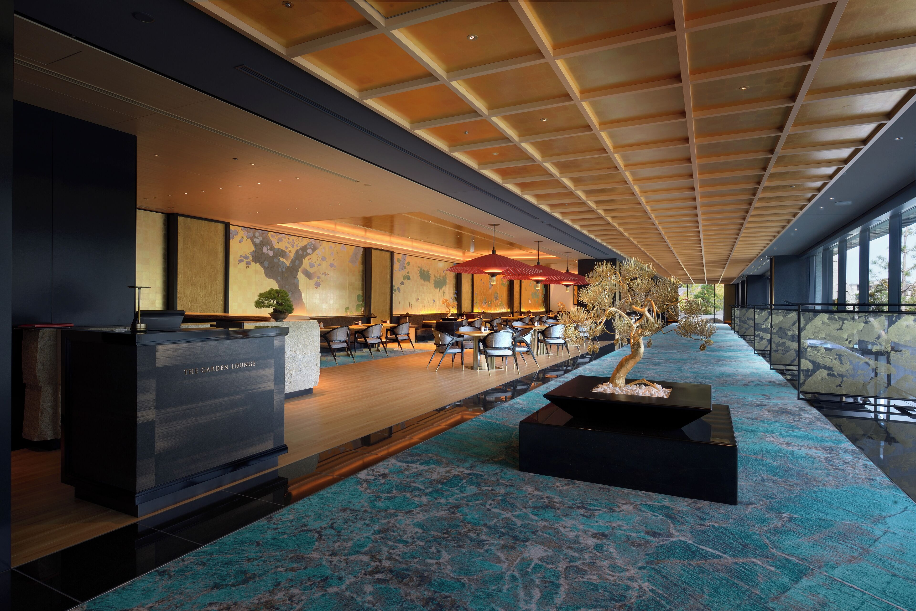 A modern lounge area with a long counter, seating, and a decorative plant centerpiece.