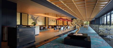 A modern lounge area with a long counter, seating, and a decorative plant centerpiece.