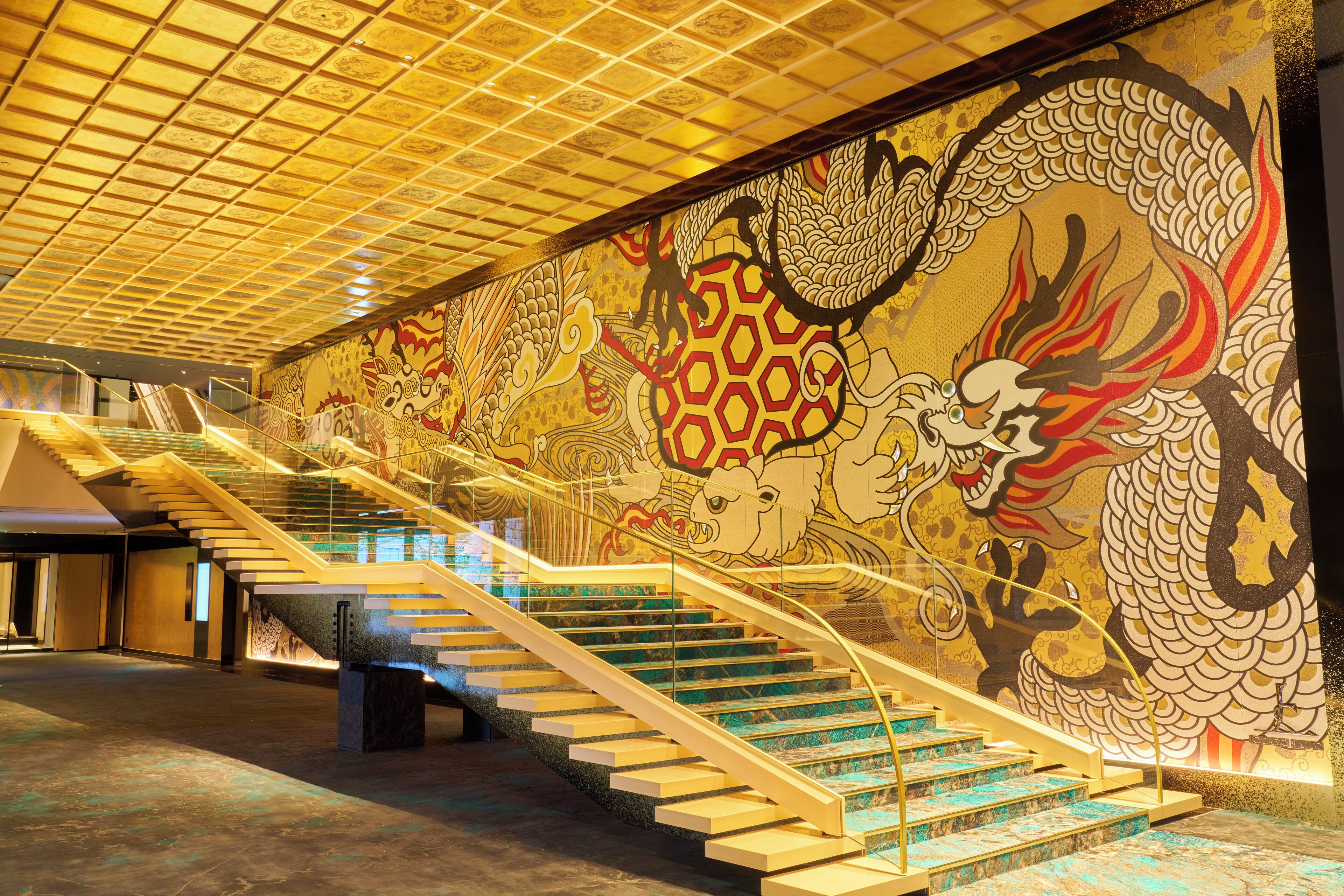 A staircase with a dragon mural on the wall, a modern design with glass railings, and a patterned ceiling.