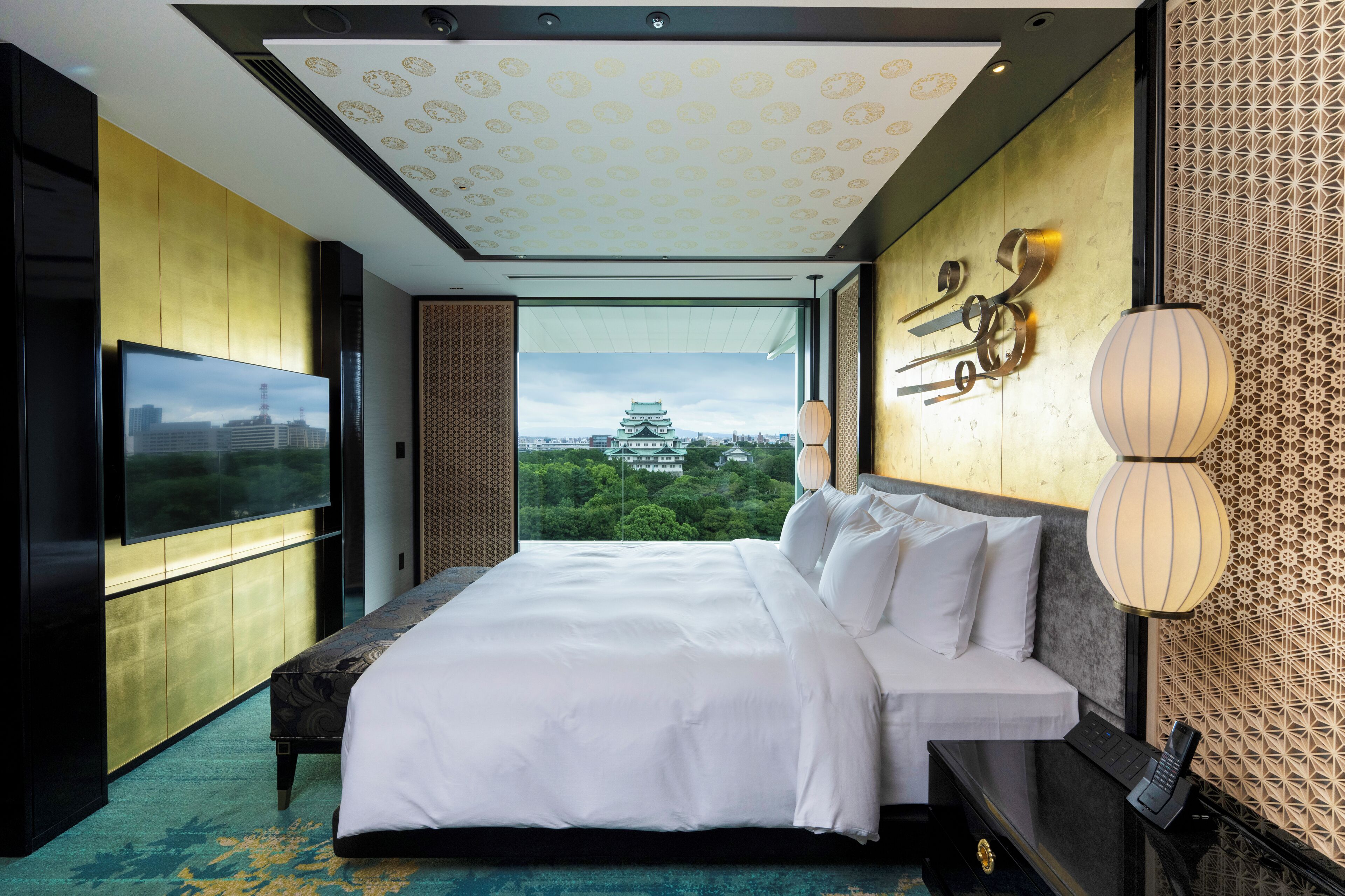 A modern hotel room with a large bed, a flat-screen TV, and a view of a traditional building.