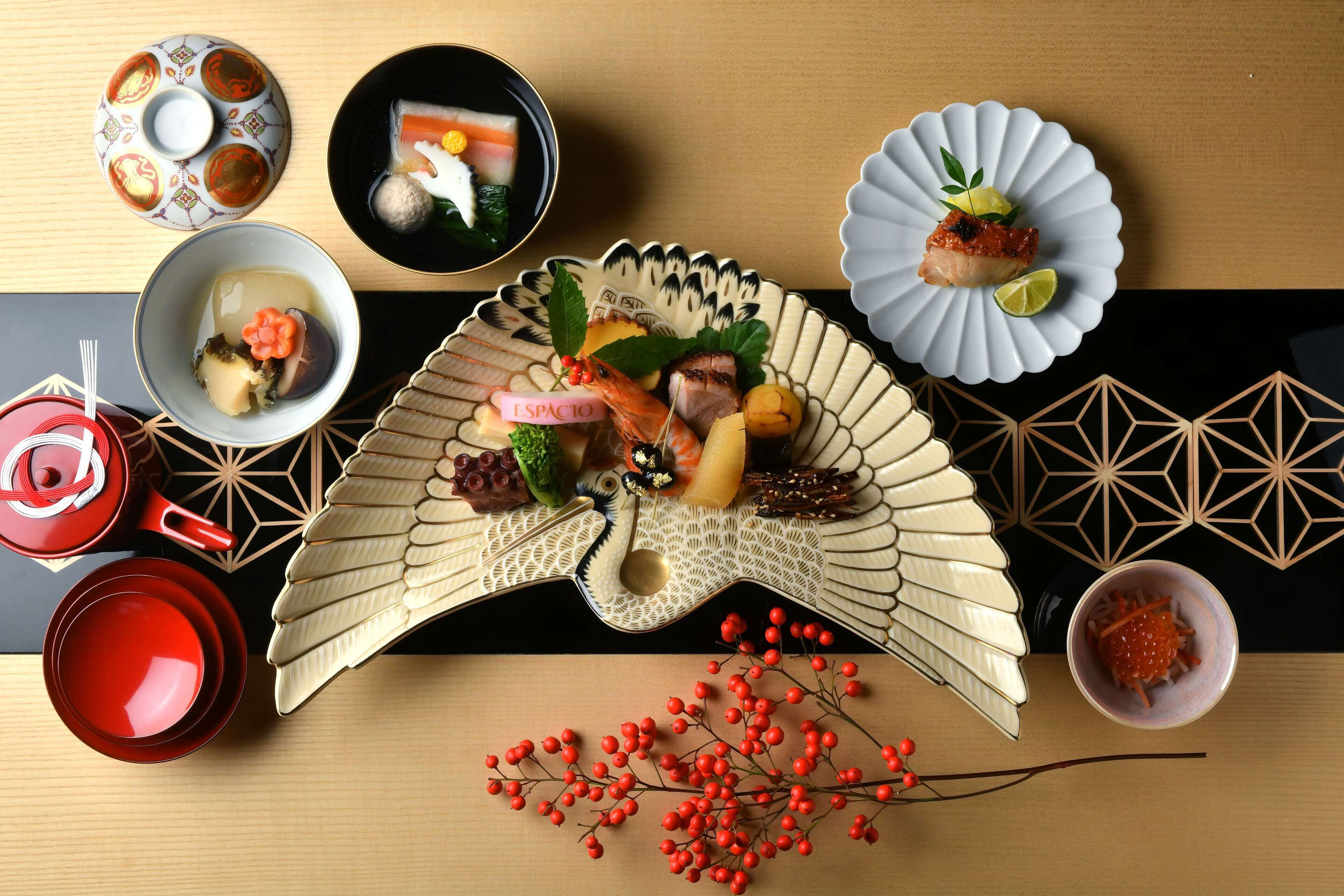 A dining table with various dishes, including sushi, sashimi, and a decorative fan.