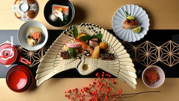 A dining table with various dishes, including sushi, sashimi, and a decorative fan.