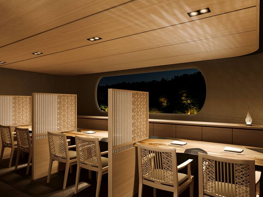 Un restaurante con muebles de madera y vistas a árboles por la noche.