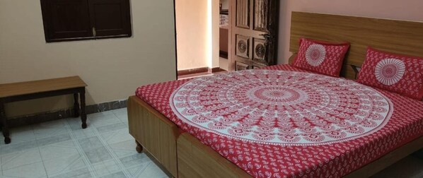 A bedroom with a round bed, a wooden bench, and a wardrobe. - Sankatha Guest House (VARANASI)