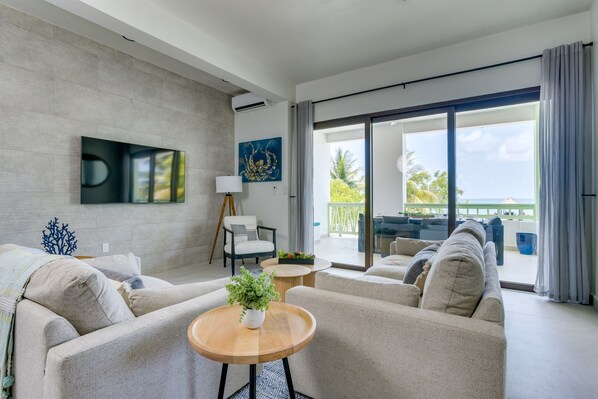 A modern living room with a sofa set, a coffee table, and a TV mounted on the wall.