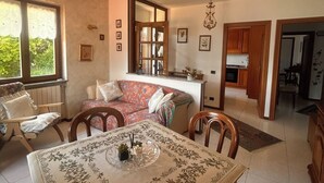 Amplia sala de estar con mesa de comedor, sofá y cocina al fondo.