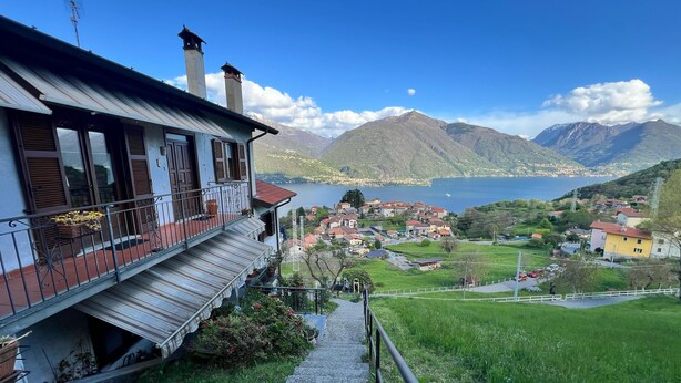 Una casa con balcón que da a un lago y montañas.