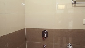 Um espaço de chuveiro pequeno, com azulejos, um chuveiro manual e uma torneira fixada na parede.