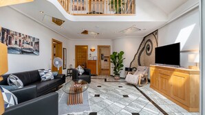 Ein modernes Wohnzimmer mit einem schwarzen Sofa, einem Glastisch, einem Fernseher und einem Holzschrank.