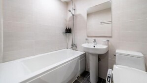 Moderni kylpyhuone, jossa on kylpyamme, pesuallas ja wc.