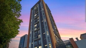 Un edificio alto con varios pisos, posiblemente residencial u oficinas, con un cielo despejado al fondo.