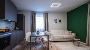 A modern kitchen with a dining area, a white sofa, and a green accent wall. - Family apartment in Schwaz (Schwaz)