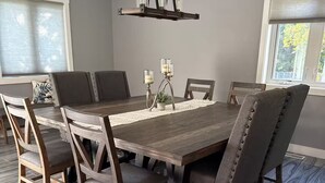 Une salle à manger avec une grande table en bois, six chaises et un lustre.