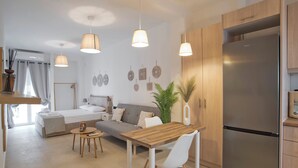 A modern kitchen with a wooden table, white chairs, and a stainless steel refrigerator. - SILIA Reno Studio Athens Ambelokipi Metro (Athens)