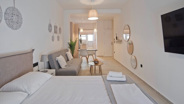 A hotel room with two beds, a sofa, a dining table, and a TV. - SILIA Reno Studio Athens Ambelokipi Metro (Athens)