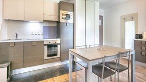 A modern kitchen with a microwave, oven, and dining table with chairs.