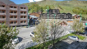 A hotel with multiple floors, a parking lot, and a mountainous backdrop.