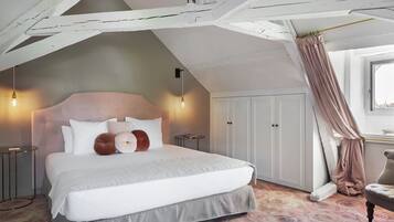 Ein Schlafzimmer mit einem großen Bett, einem Kleiderschrank, einem Sessel und einem Fenster mit Vorhängen.