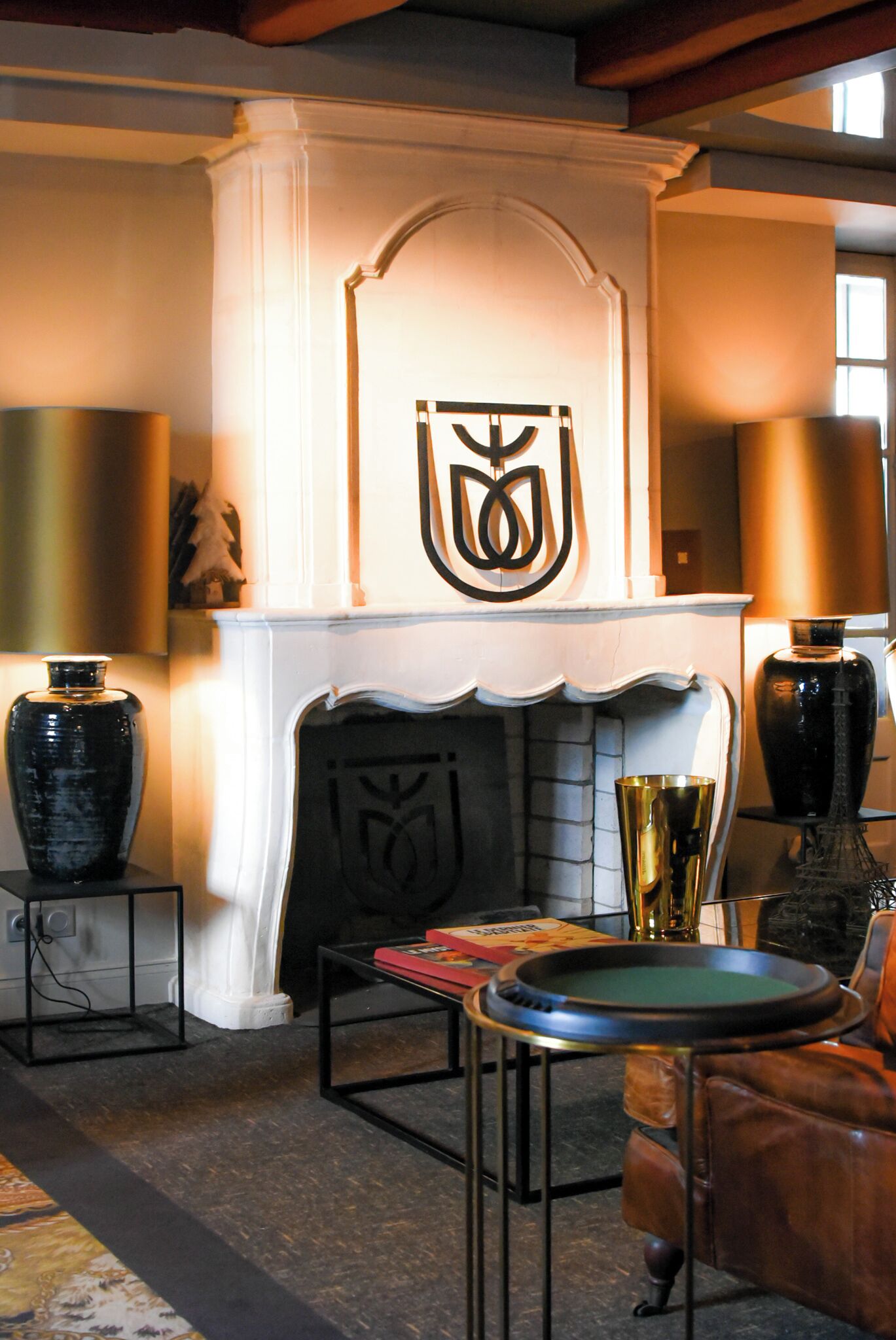 A room with a fireplace, a leather armchair, and a table with a green playing card.