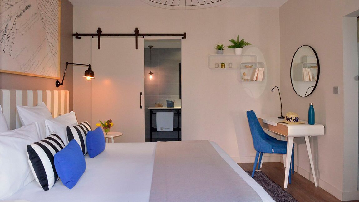 Een moderne slaapkamer met een bed, nachtkastjes, een bureau en een stoel. Er is een spiegel, een plank met planten en een wand met een kaart.